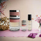 Trussardi Parfumset mit drei eleganten Flakons auf rosa Untergrund, umgeben von Blumen.