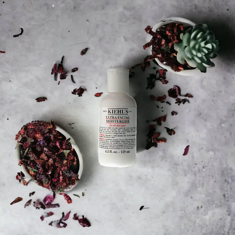 Kiehl’s Ultra Facial Moisturizer auf Marmor mit getrockneten Blüten und Sukkulente