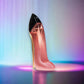 Parfümflakon in High-Heel-Form, glänzend rosa mit schwarzer Kappe, vor buntem Hintergrund