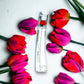 Flower by Kenzo Eau de Parfum Flakon mit roten und violetten Tulpen auf weißem Hintergrund