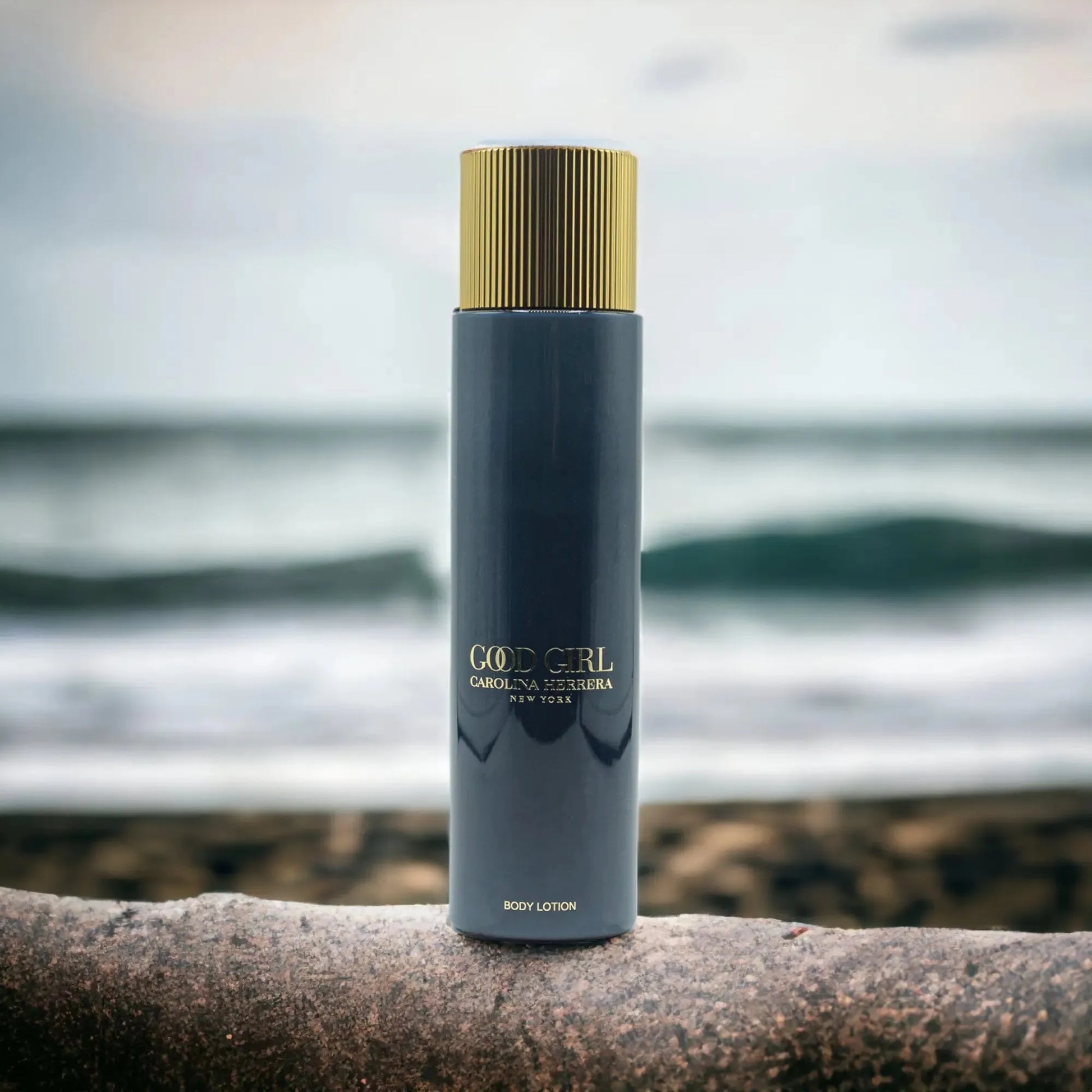 Good Girl Body Lotion von Carolina Herrera, eleganter Flakon am Strand mit Meer im Hintergrund