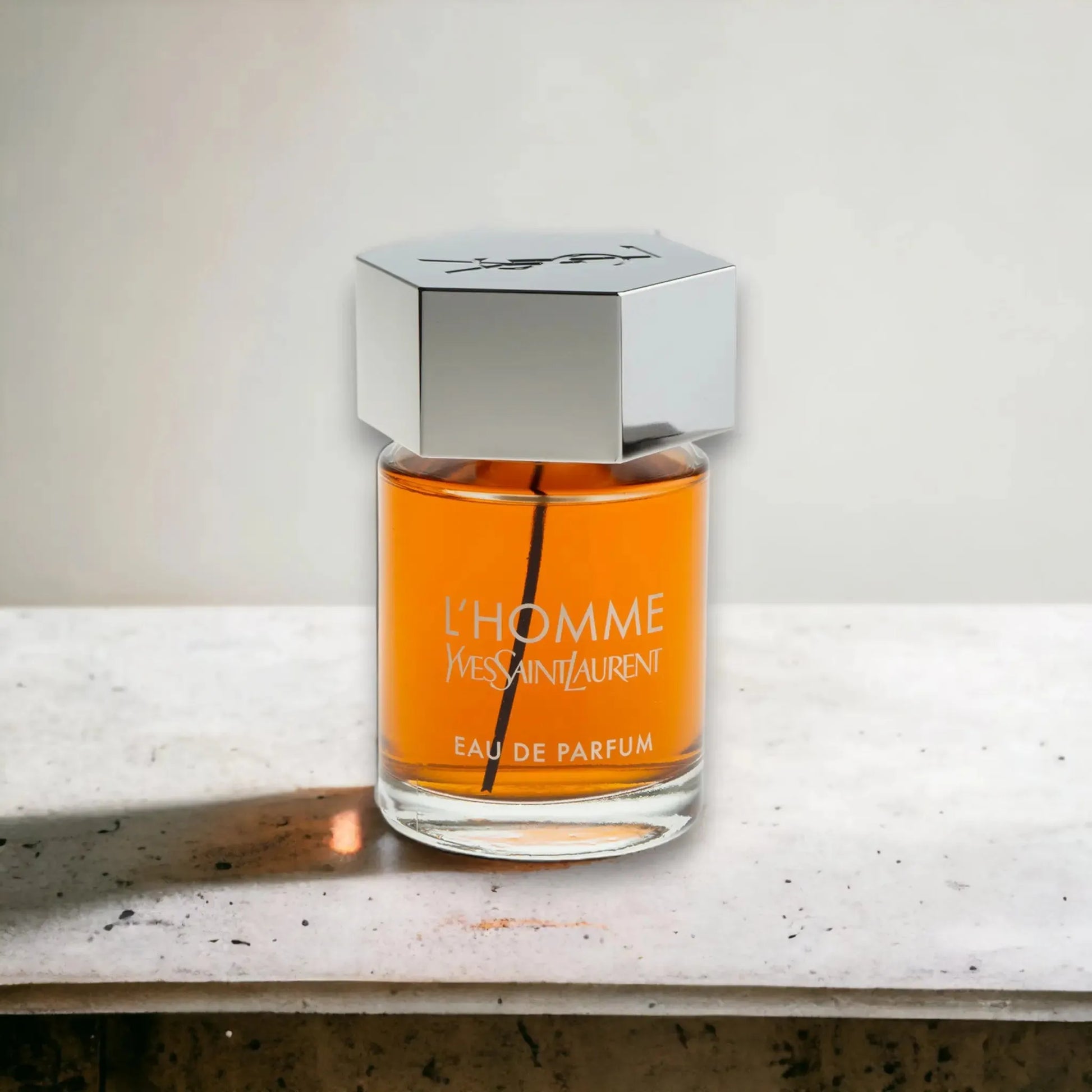 Parfumflakon L'Homme Eau de Parfum mit silbernem Verschluss auf hellem Stein