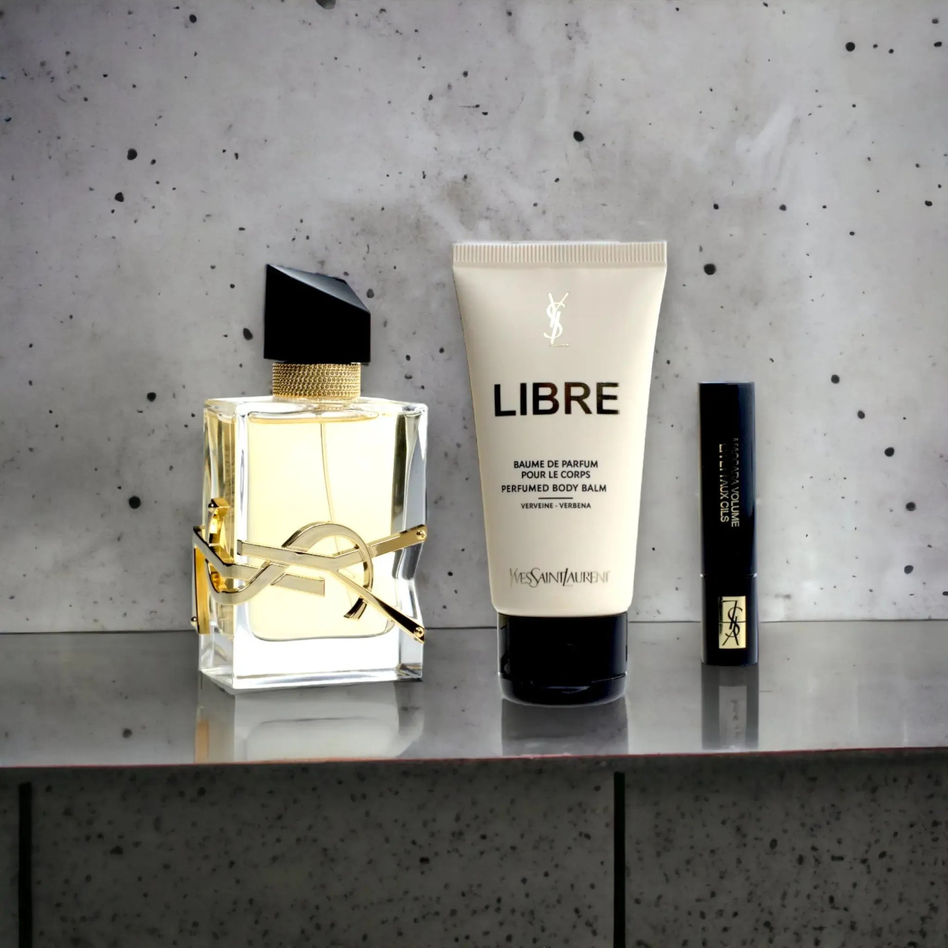 Geschenkset mit Parfumflakon, Body Balm und Miniatur auf grauem Hintergrund, Yves Saint Laurent Libre