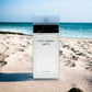 Parfümflakon Dolce & Gabbana Light Blue Eau de Toilette auf Sandstrand mit Meer im Hintergrund