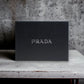 Schwarze Prada Geschenkbox für Luxusparfum auf hellem Steintisch, minimalistisches Design