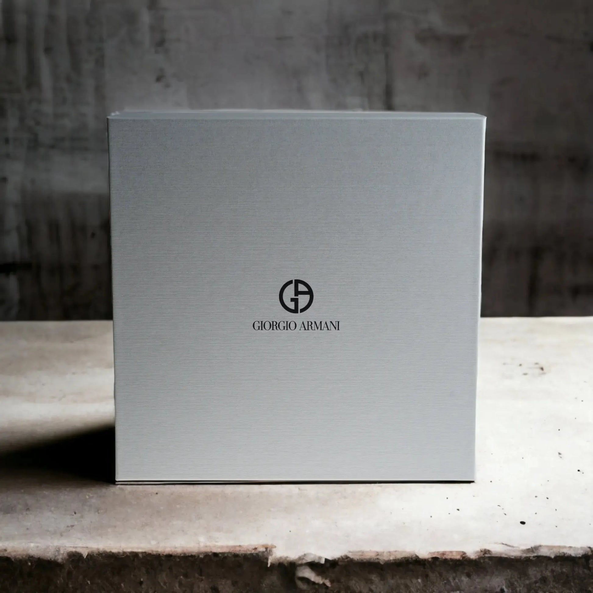 Elegante, graue Geschenkbox mit Giorgio Armani Logo, präsentiert auf hellem Untergrund.